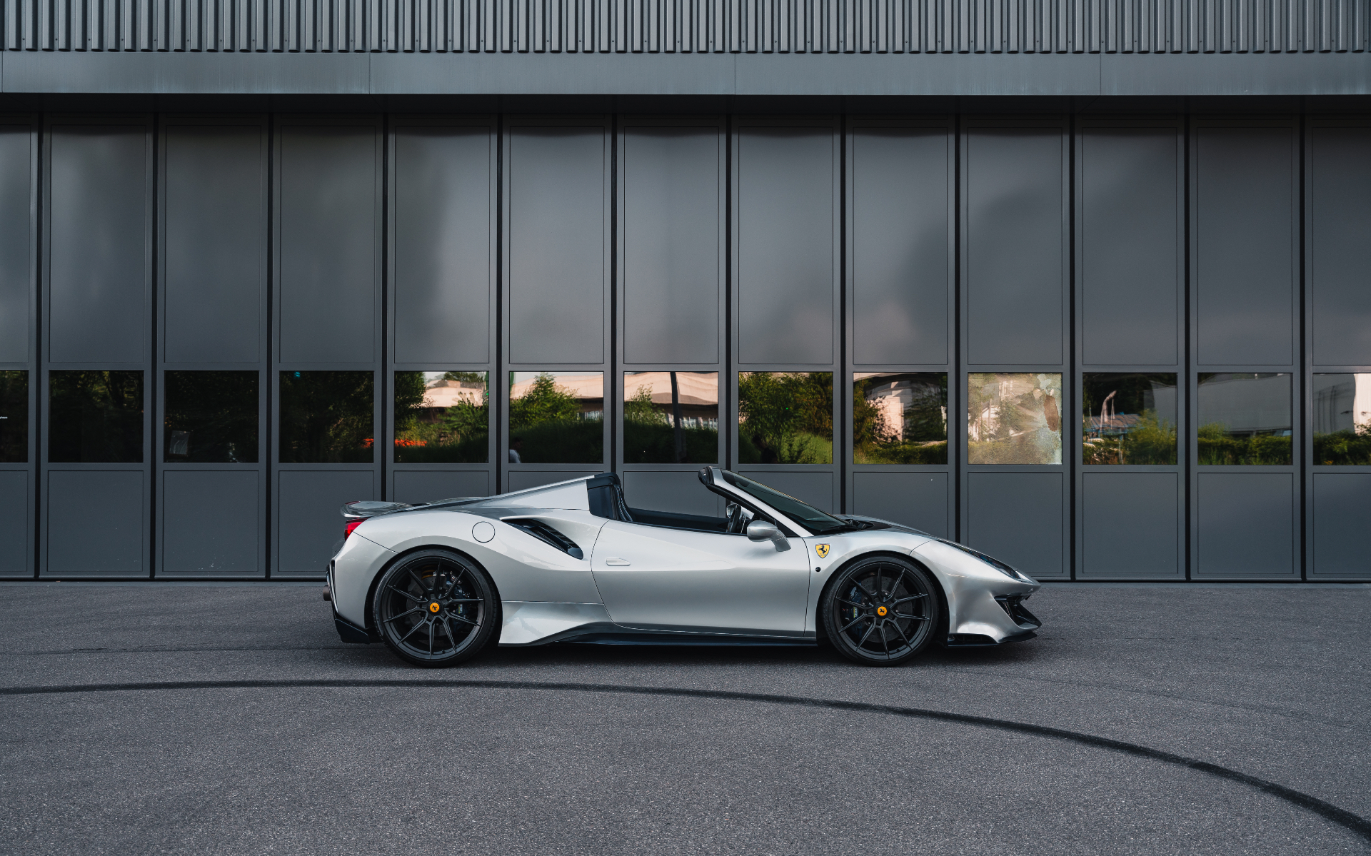 White Ferrari convertible parked in front of a modern building