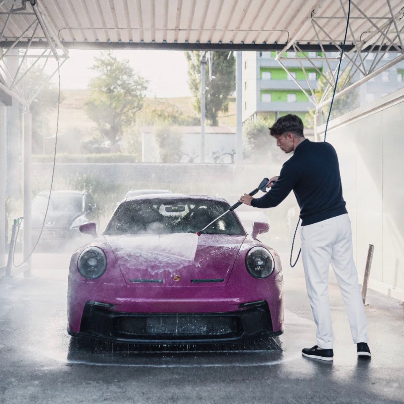 Sam Joshua Halef washing a purple Porsche at a car wash